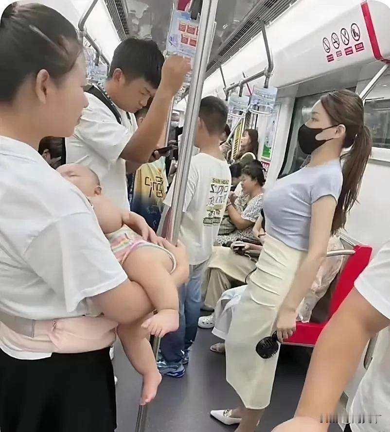 在拥挤的地铁车厢里，一位面容疲惫的女人，正抱着婴儿艰难地站着。那婴儿在怀中不安