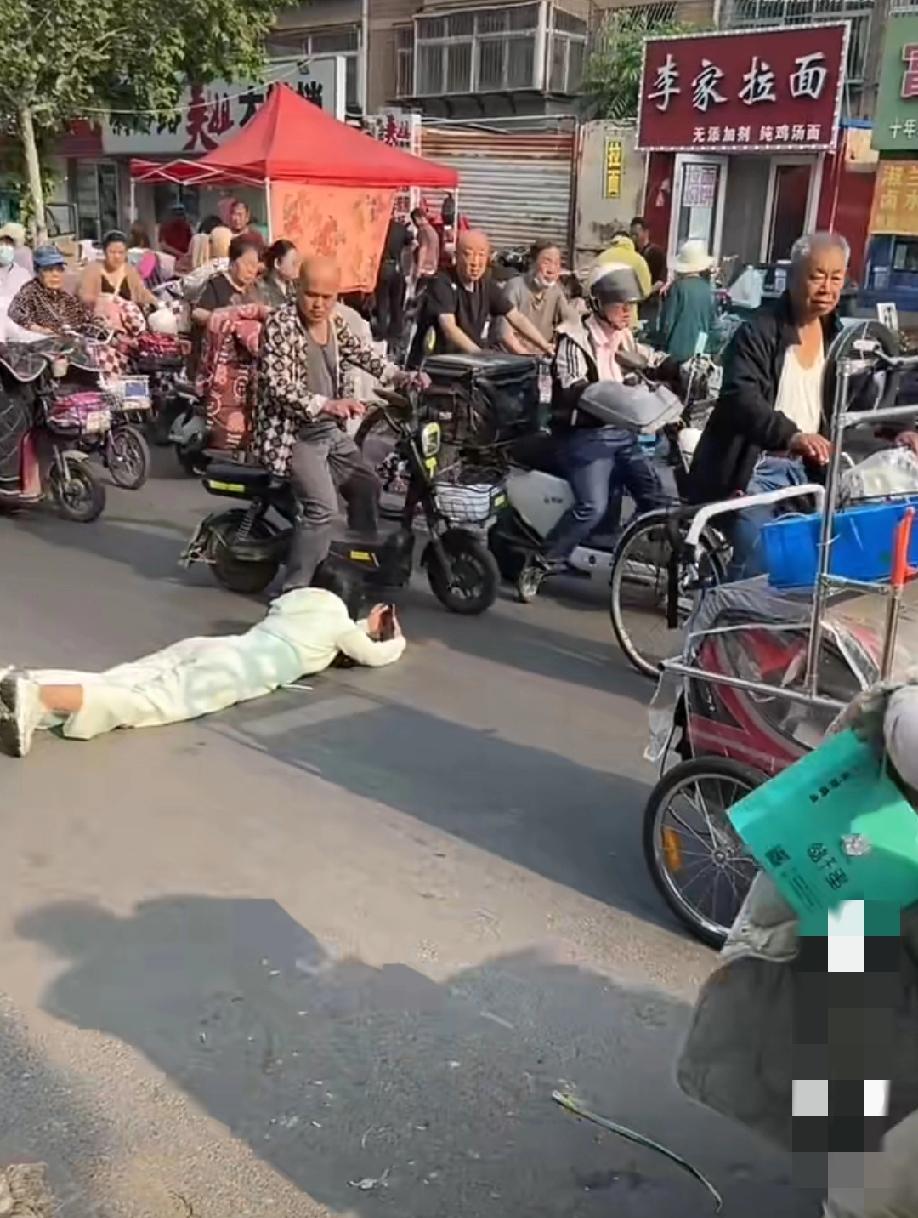 5月15日，山东德州。一处非常热闹的早市街头，一名女子直接趴在地面来回打滚，全程