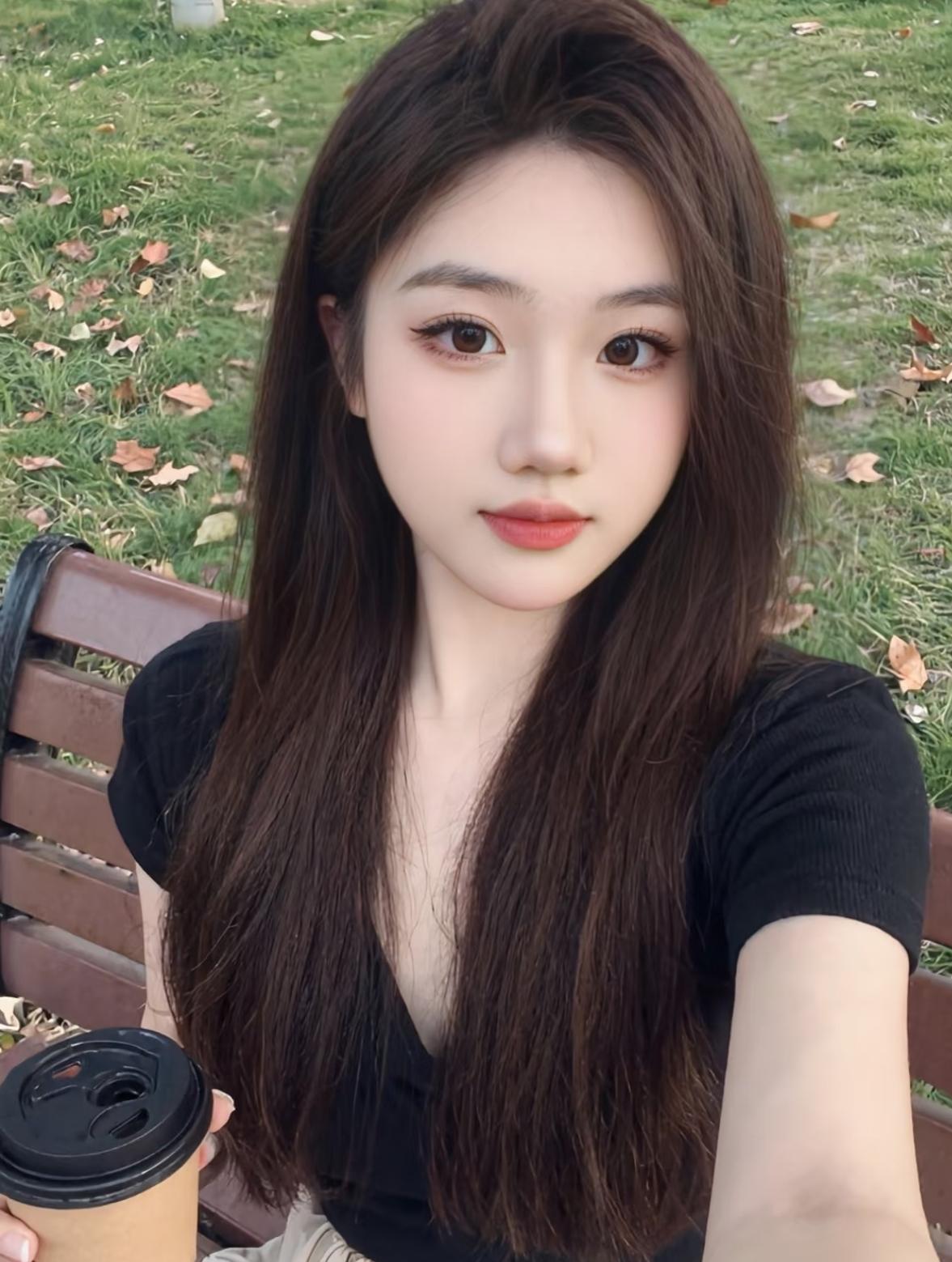 长发妹子在公园喝咖啡自拍。
