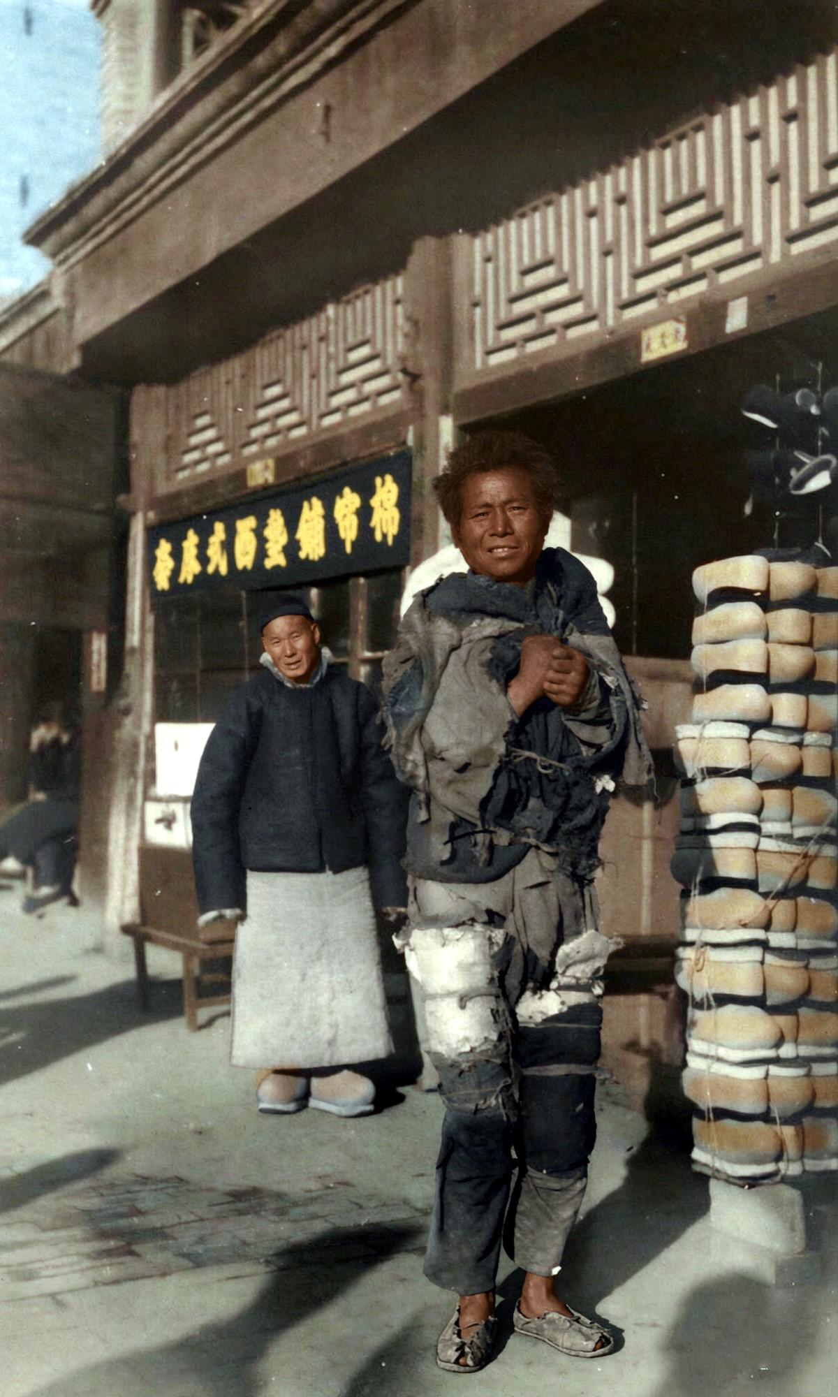 民国时期的北平街头，一家挂着“棉帘铺垫西式床套”招牌的商铺门前，整齐堆叠着如小山