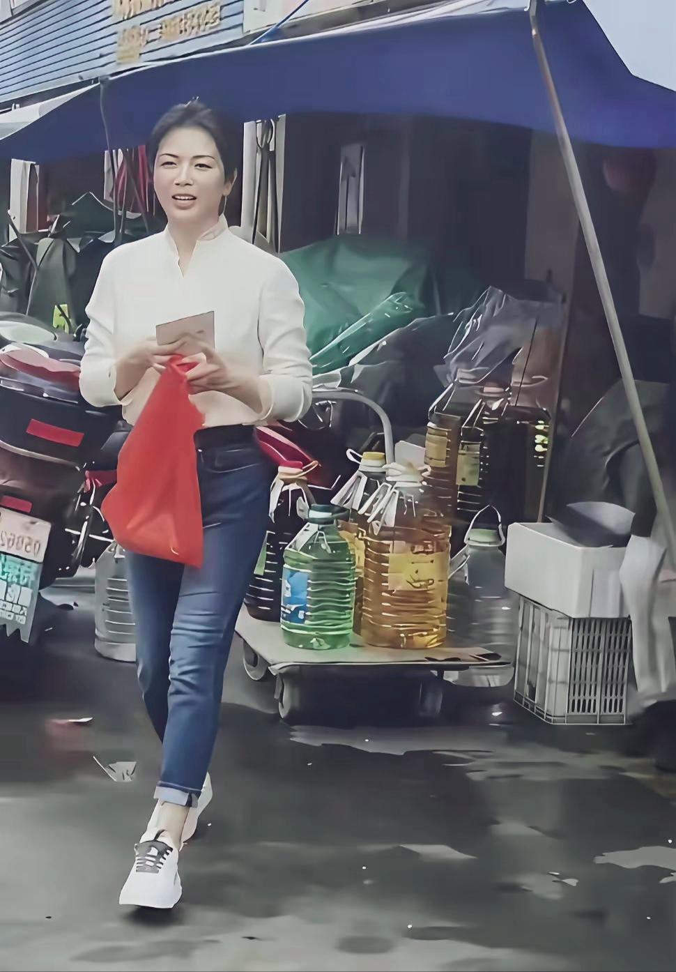 刘涛米白长袖上衣，配修身卷边牛仔长裤，脚踩小白鞋，全程手持红色塑料袋，像寻常出门