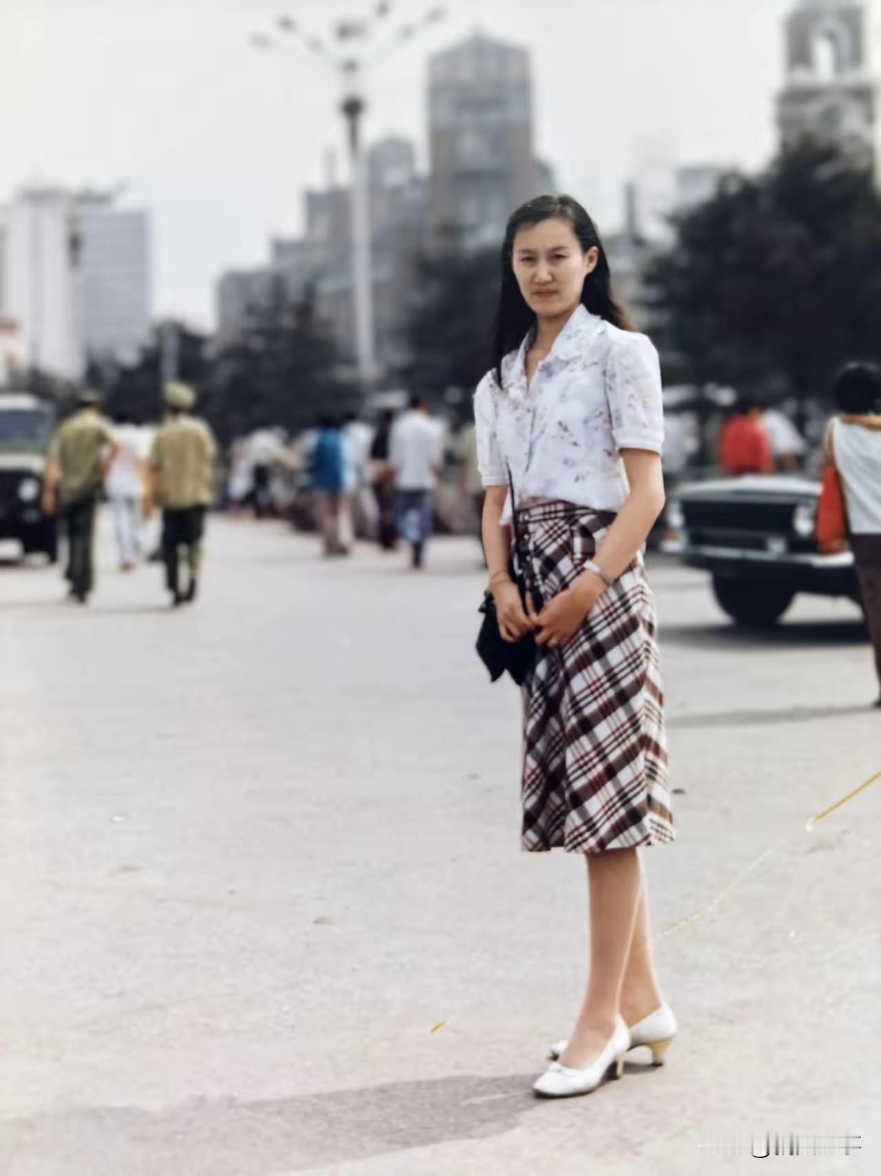 1982年，大连站前，一名纺织厂女工的青春留影。镜头下，她站在街道上，柔顺长发垂