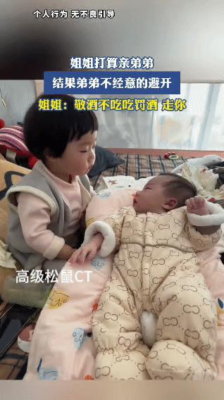 画面里的小姐姐噘着嘴凑到婴儿弟弟跟前，满心欢喜想亲一口，结果弟弟脑袋一歪，干脆利