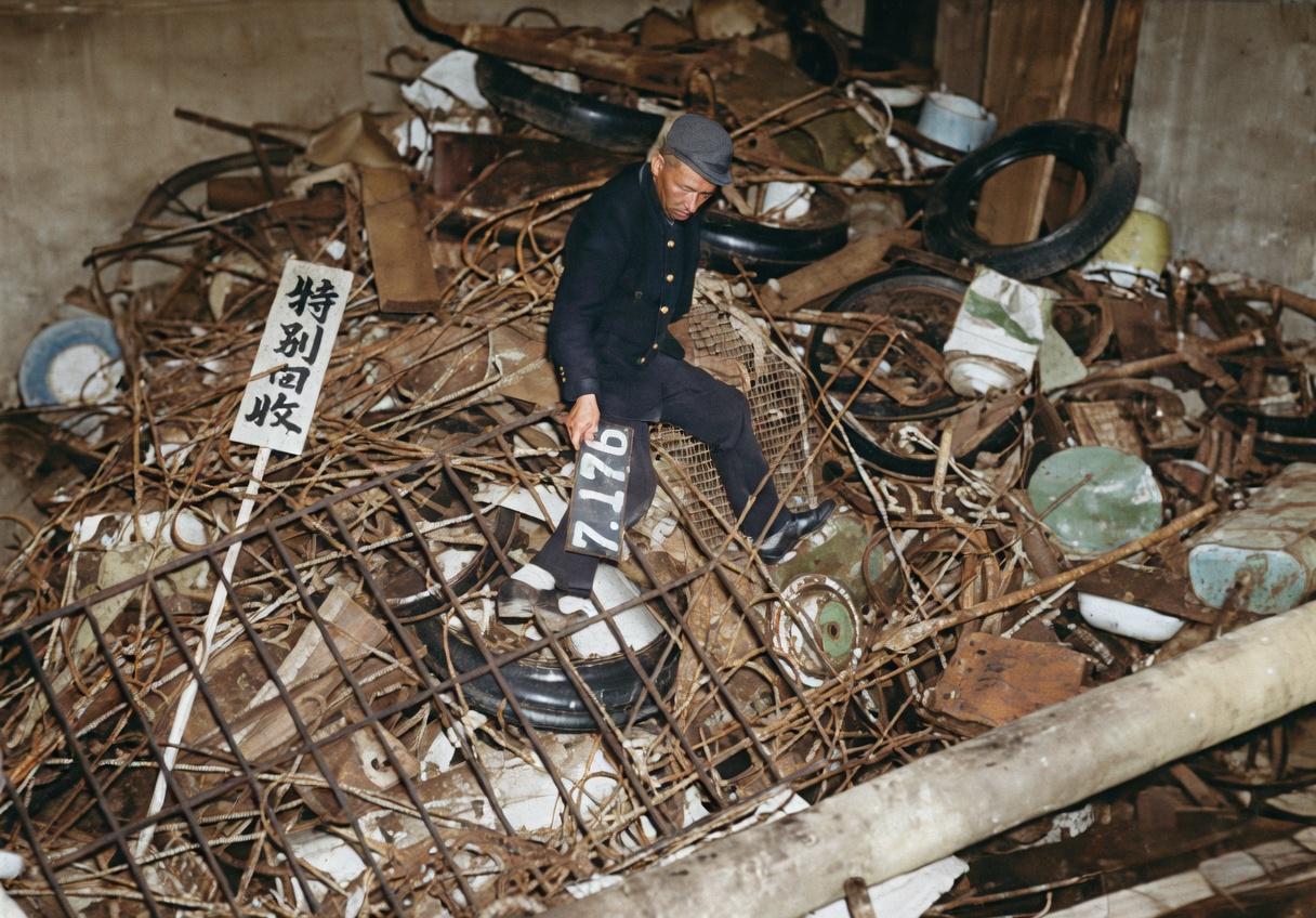 照片里，小山一样的破铜烂铁堆上插着“特别回收”的木牌，有人正蹲在废料里分拣——这