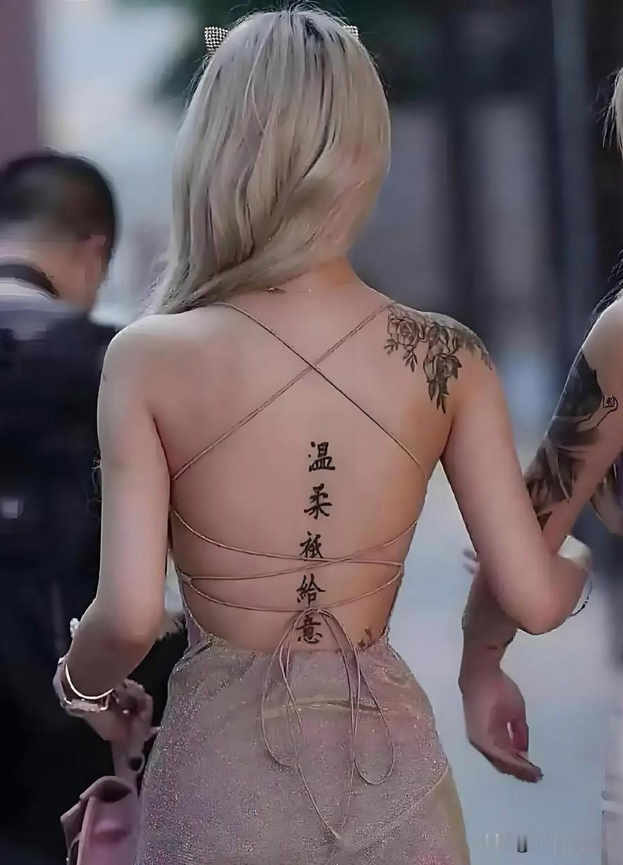 刷到这张照片，像撞见一帧独特的风景——她一袭露背长裙，长发散落，脊背上“温柔只给
