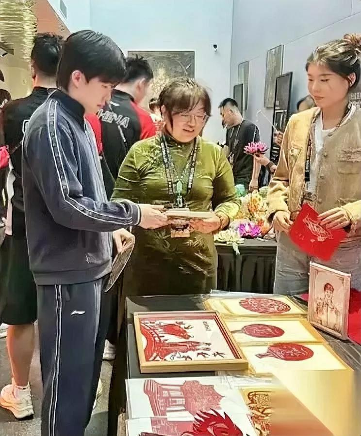 晚宴上，王楚钦捏着剪纸，眼神却黏在莎莎那张上，像被磁铁吸住。我隔着屏幕都替他急：