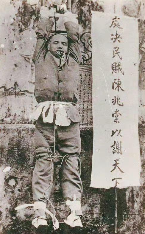 这张照片记录的是清末潮州知府陈兆棠被处决后的场景，照片中他被缚于竹梯上，旁侧标语