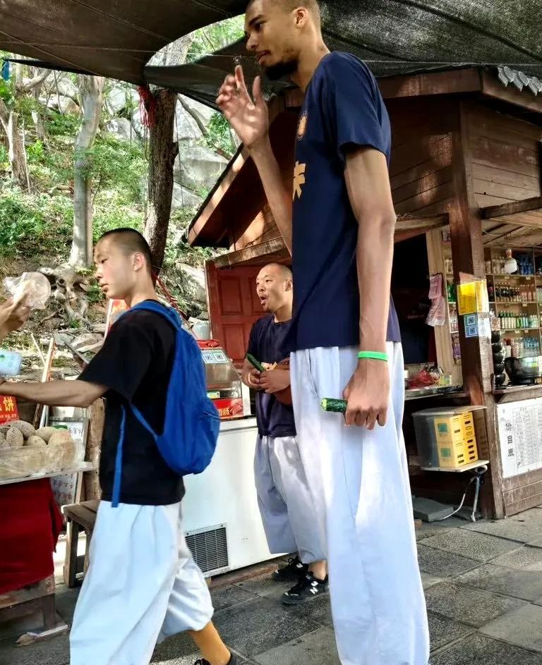 文班亚马与少林寺师兄们一起去小卖部买东西，这根黄瓜在他手中显得格外迷你。