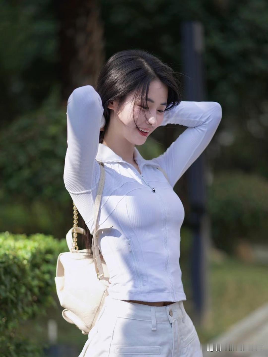 阳光明媚的午后，微笑的少女在绿意盎然的背景下，散发着青春的活力与美好。