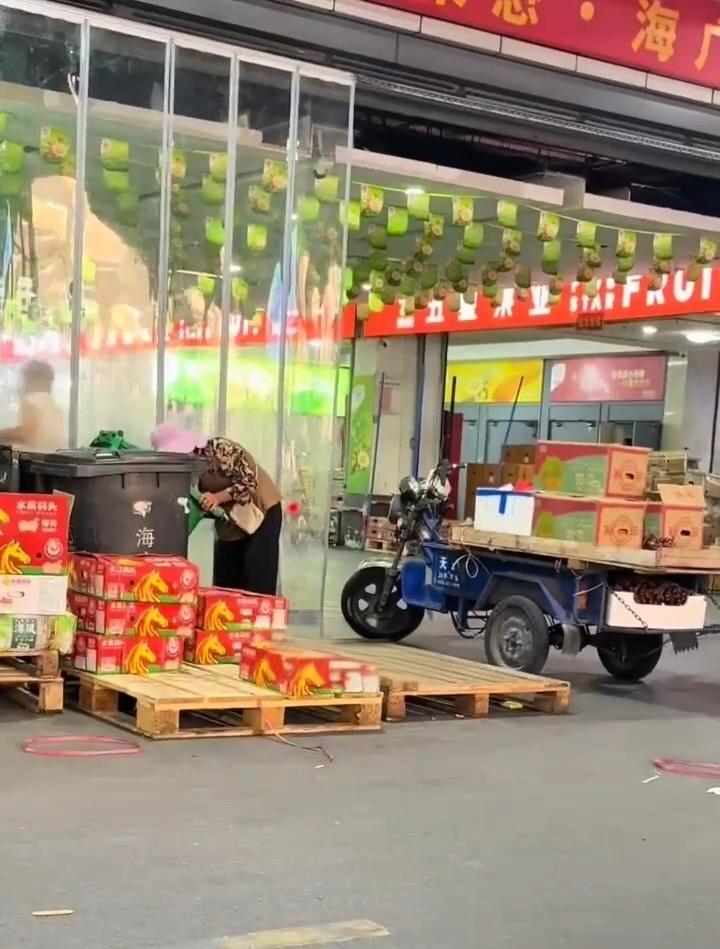嘉兴水果市场一角，一位老阿姨在捡商家丢掉的水果。看这位阿姨的装备，不像是捡来