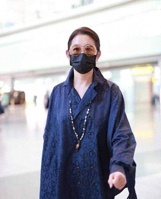 倪萍再次穿着衬衫现身机场。这次她搭配了牛仔裤，露出了脚踝，让她看起来比平时时尚了