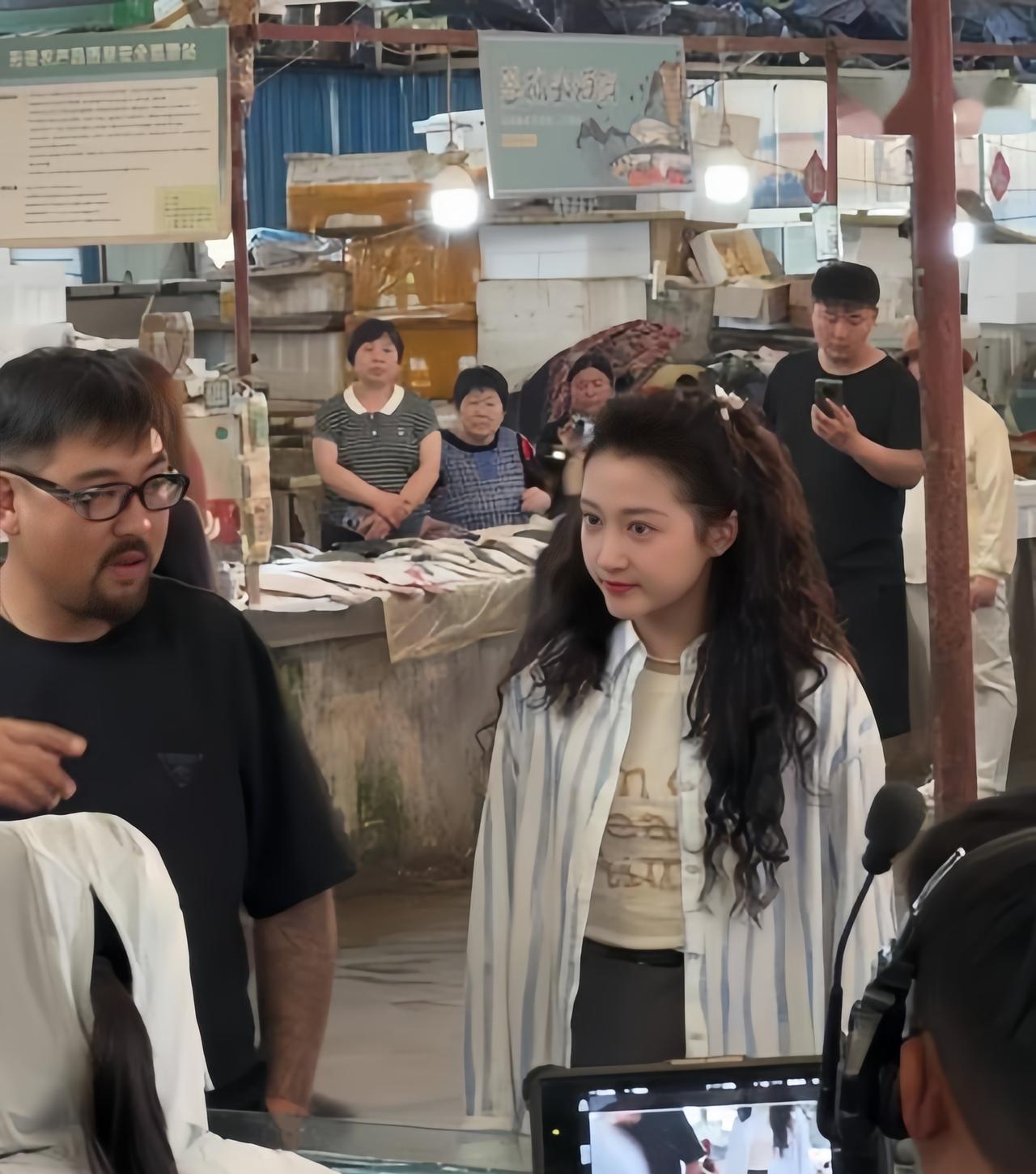 5月25日，关晓彤现身山东石岛，在一农贸市场拍戏，她单肩背着布袋，正在发传单并与