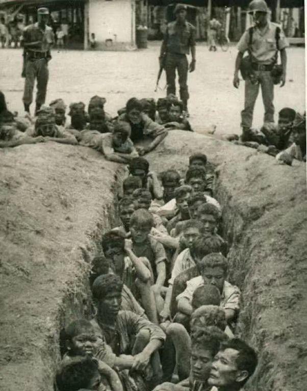 1965年，印尼大屠杀。人们整齐地排成两列，坐在土坑中，他们即将被一个接一个地处