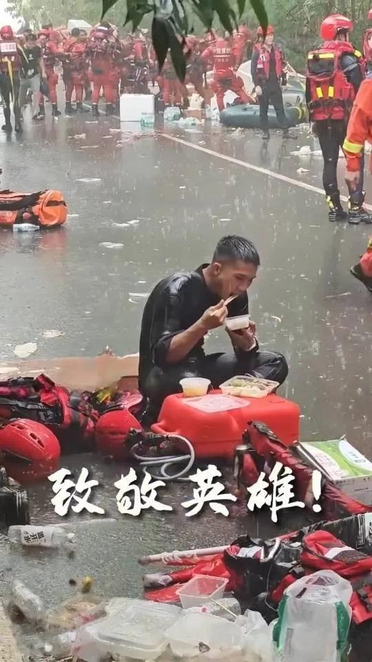 这张救援照片，最戳我的不是他在雨里吃饭。而是不远处明明有帐篷，他却坐在原地，一动