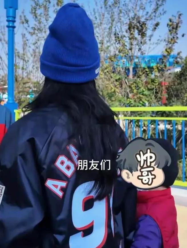 张柏芝带小儿子去新加坡环球影城玩，在机场穿宽松格子衬衫配棕色裙子，跟儿子一起比耶