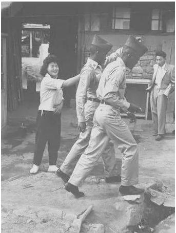 1952年韩国民宅，女子服务美军露出满意笑容，丈夫一旁愁眉不展。1952年冬