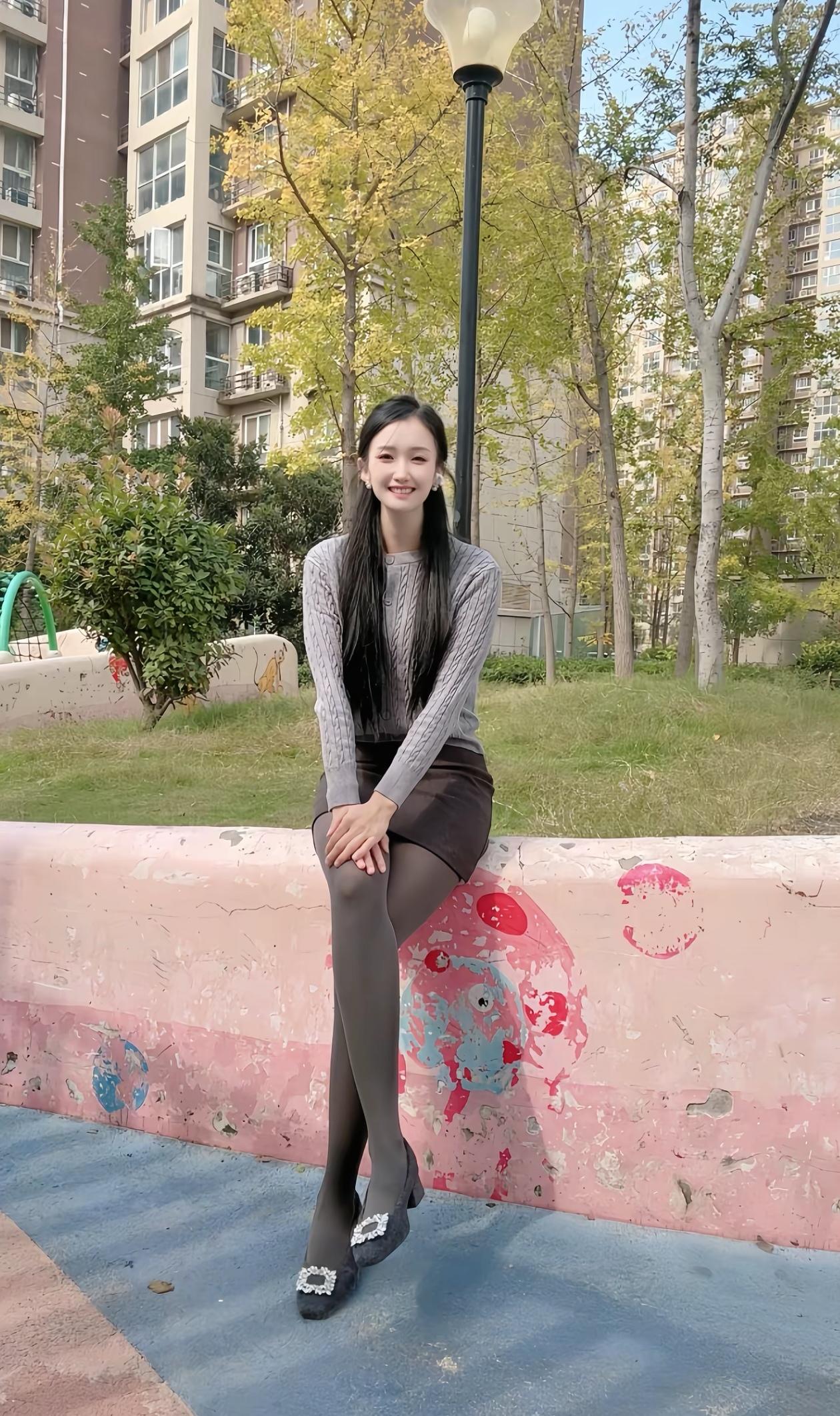 秋日暖阳下，笑靥如花的女孩坐在公园长椅上，享受着宁静的午后时光。