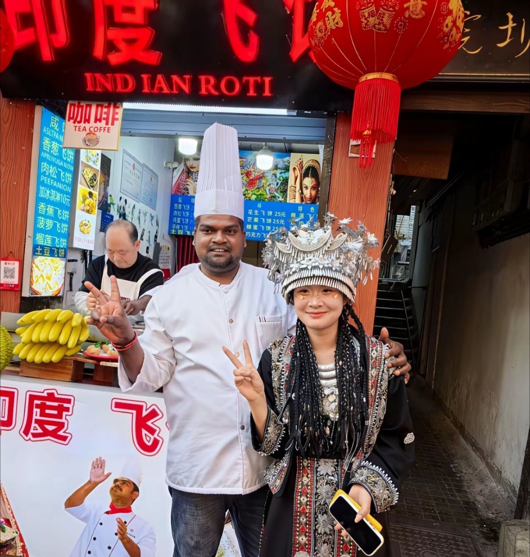 女生和卖印度飞饼的印度人合影，让人家抱着她拍照。