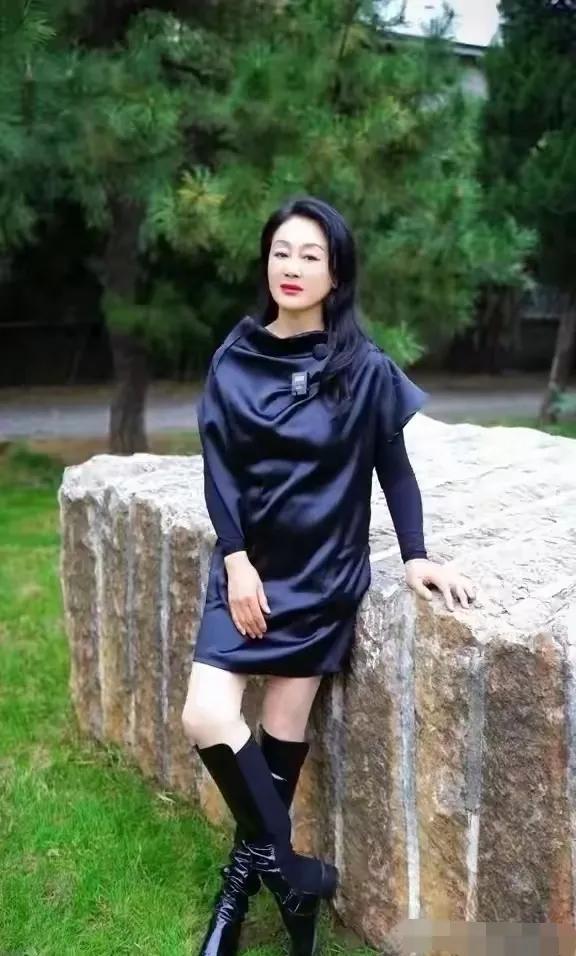王姬的美丽瞬间：王姬优雅地倚靠在石墙上，翠绿的草坪和树木形成自然背景，衬托出她从