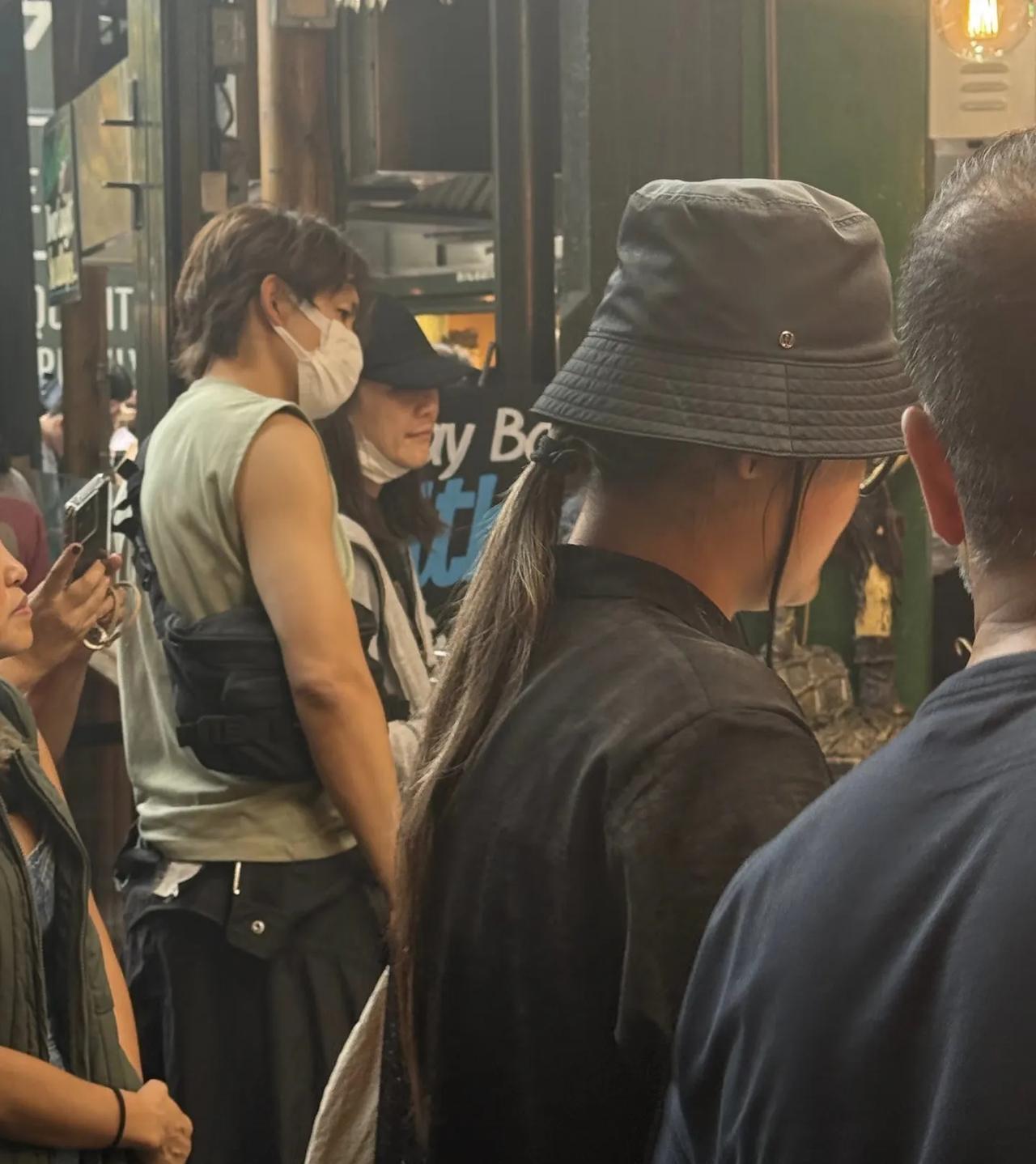 50岁钟汉良和老婆在英国伦敦的市场排队买生蚝，他穿着无袖上衣，手臂粗壮，身材练得