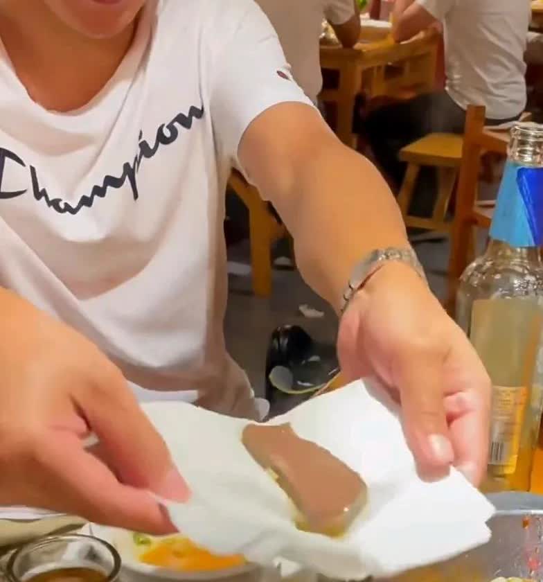男子吃火锅时，突然对锅中的鸭血有了想法，把鸭血涌之巾包好后，开始按压，按压过