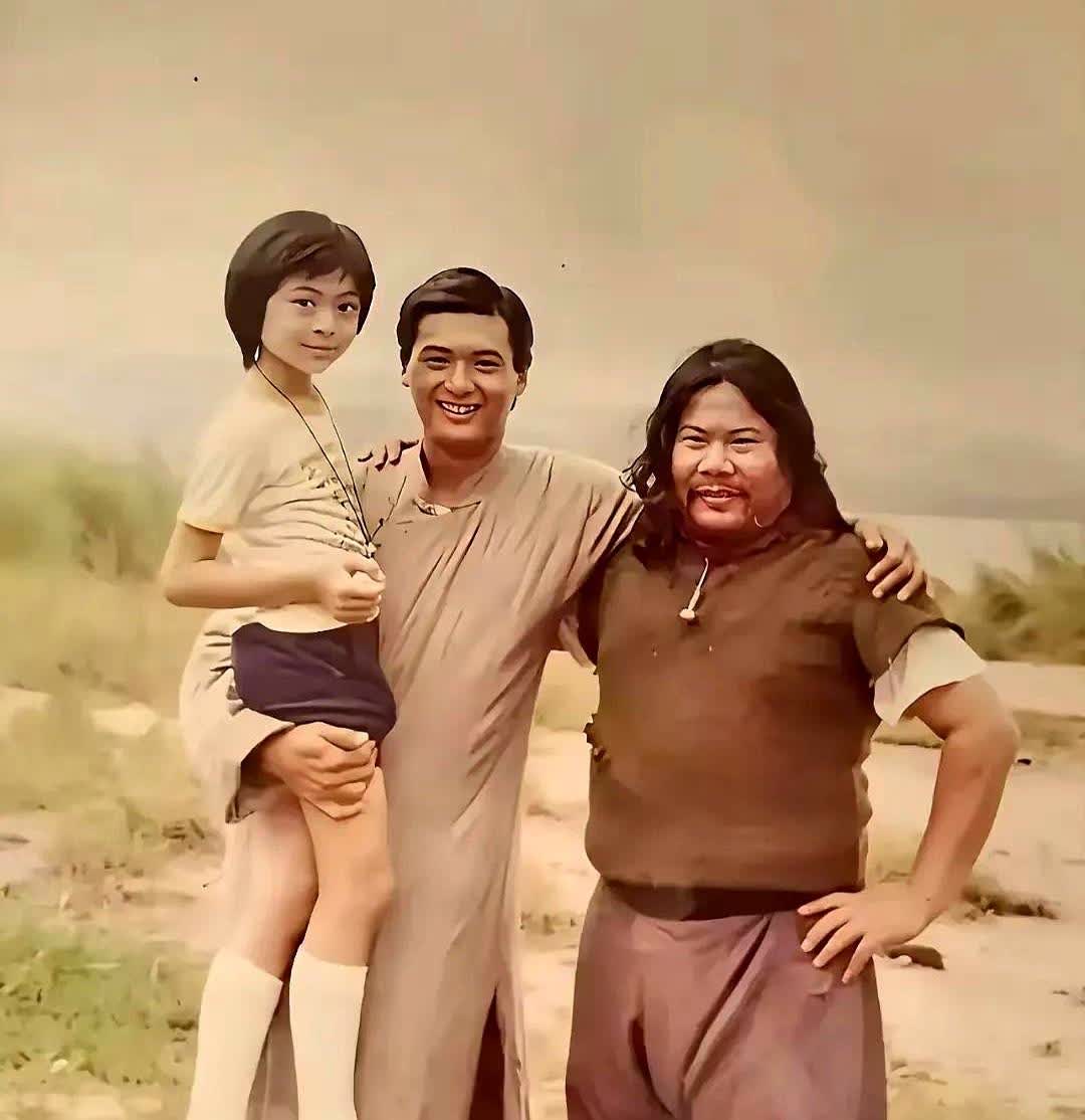 这张照片拍摄于1982年，当时27岁的周润发手上抱着9岁的樊少皇，而站在他身边的