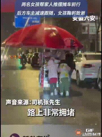 安徽六安一处街头，由于刚结束跨年夜，道路拥堵，一位摊主推着车往家里走，他的两个女