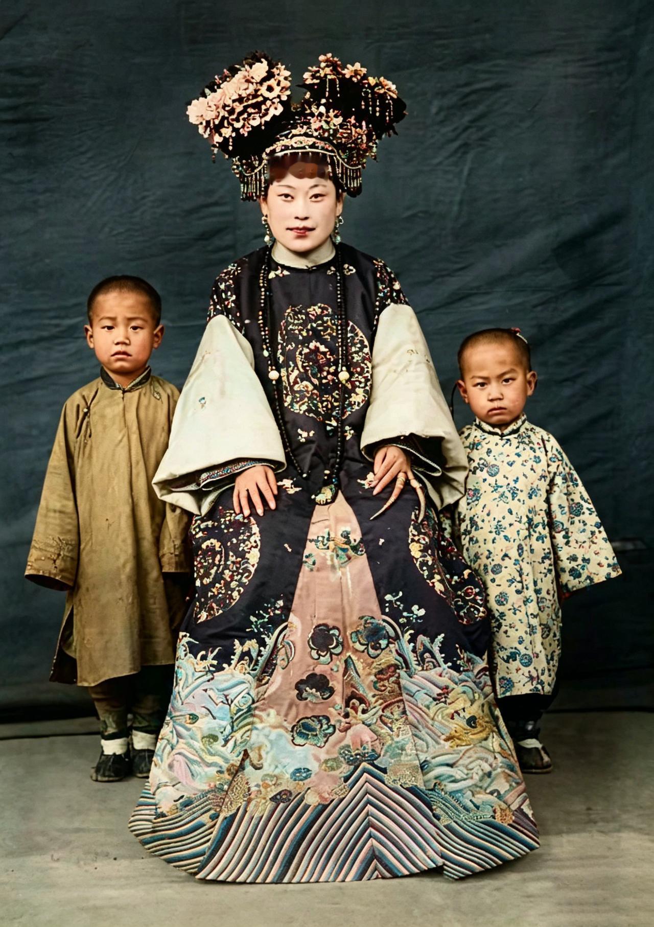 这张晚清老照片，定格了一位满族贵族女子与孩童的合影。她身着绣满龙凤纹样的旗装