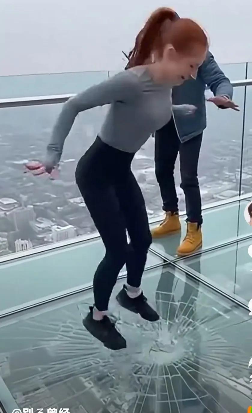 三个年轻人在玻璃栈道上，玩耍，一个女子使劲在那蹦跳，眼看着玻璃都要碎了，她还不