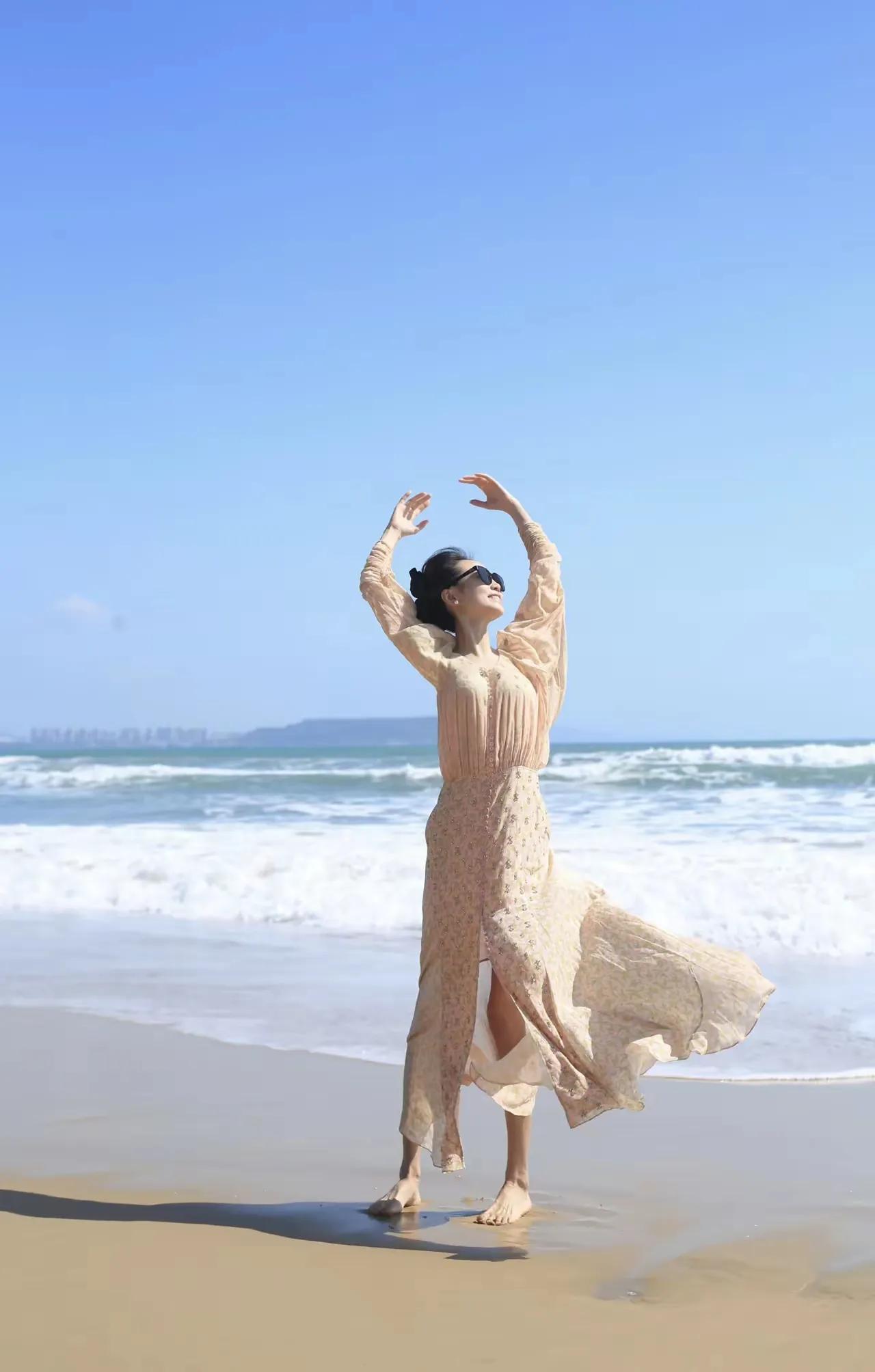 珊珊海边漫舞，大海作背景，海风为伴🌊一袭浅杏长裙，赤脚站在沙滩上，身姿轻盈曼