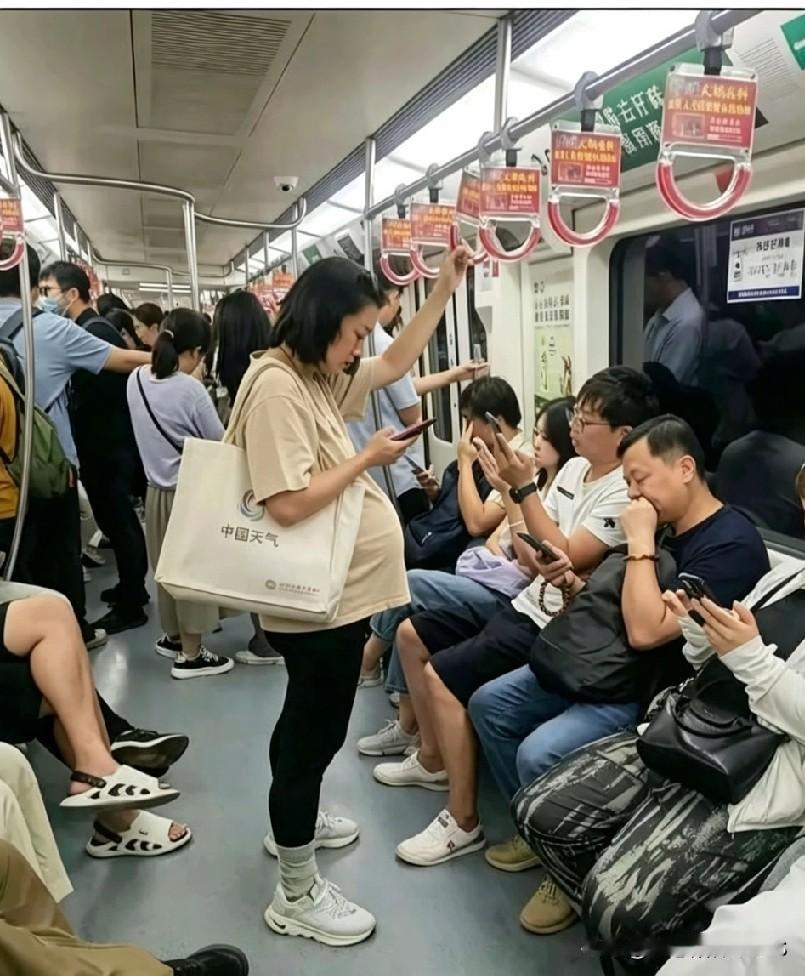 地铁里撞见这一幕，心头满是复杂的滋味，一位孕妇站在车厢当中，座位上的不少乘客都低
