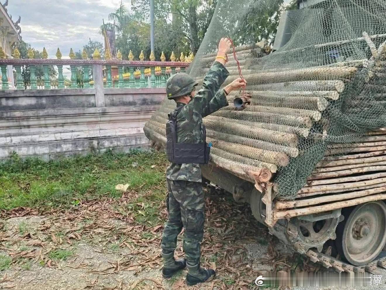 泰国士兵从一辆M113的原木装甲上取出卡住的柬埔寨PF-89火箭弹，可以看到原木