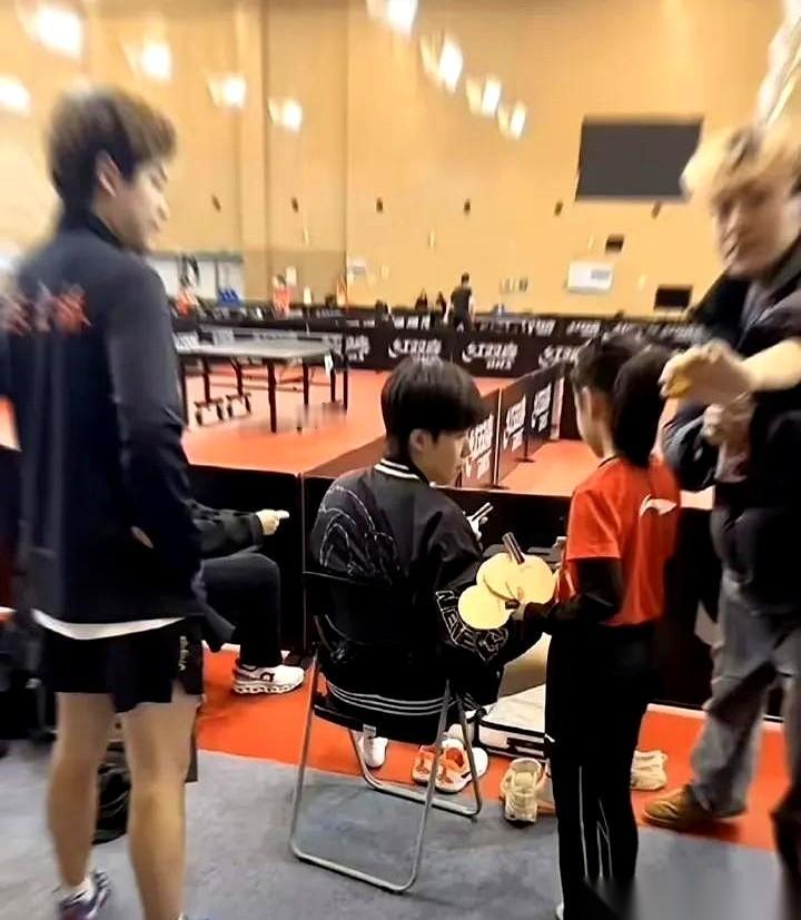 那一摞球拍，比那小女孩的个头都快高了。就这么直愣愣地递到刚下训、一身是伤的王楚