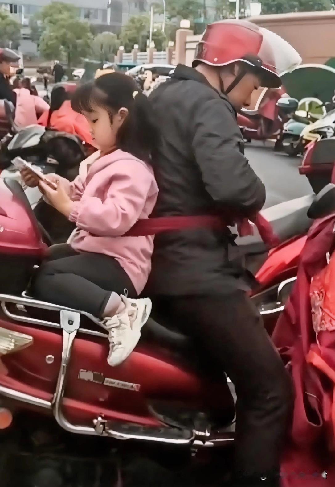 爷爷接小孙女放学，把她面朝车尾放到后座以后，自己也上了车，并戴上了头盔，接着爷爷