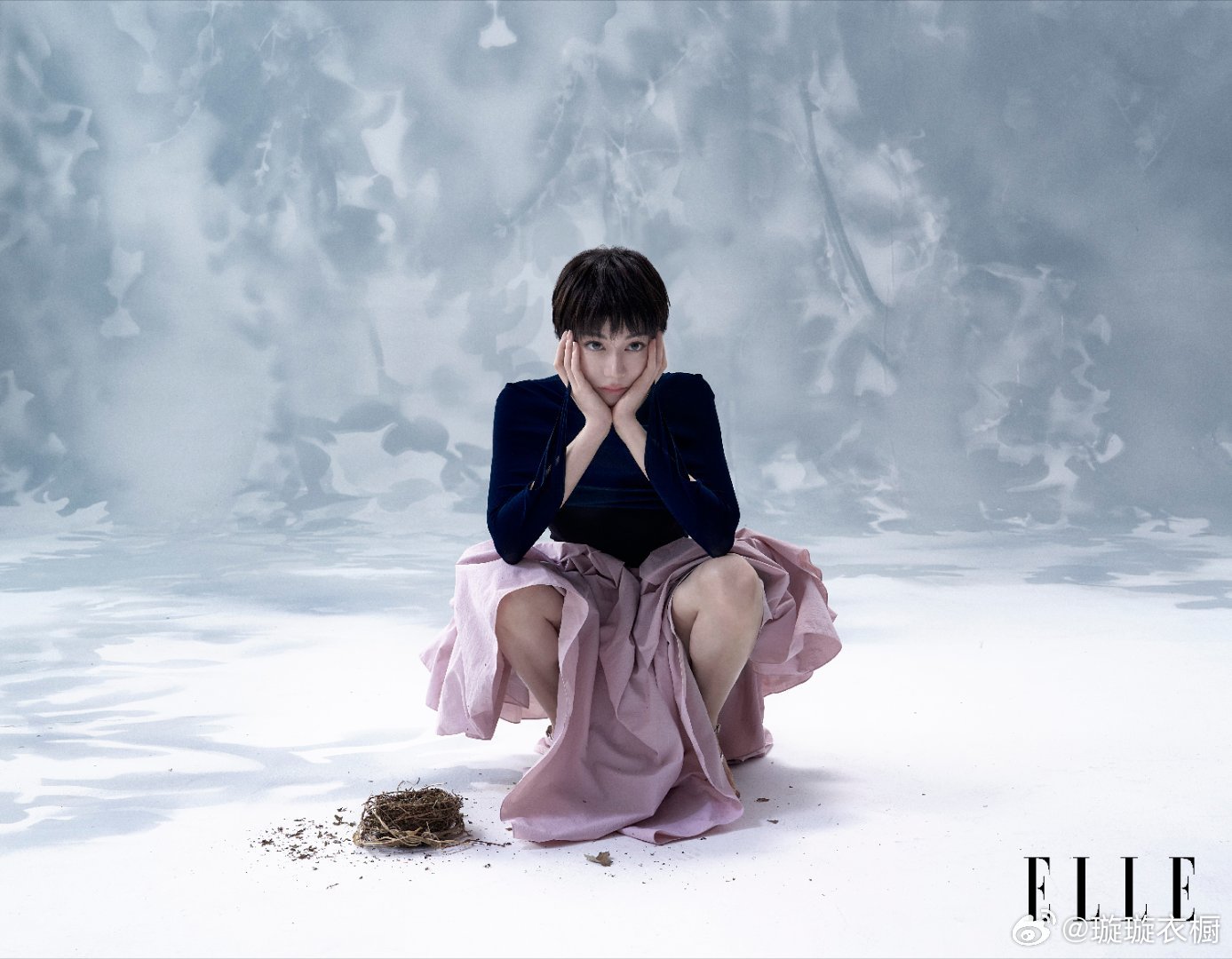 迪丽热巴暗纹大衣剪裁出冰川的棱角，手袋褶皱藏着未说的诗行黑纱帽檐垂落星河，红裙褶