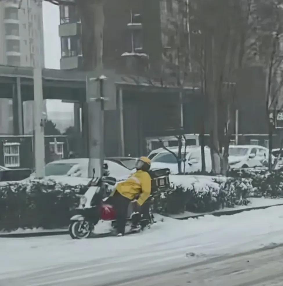 济南一名网友无意中拍到了这张照片，冰冷的雪天里，一名快递小哥躺在电动车上，像是累