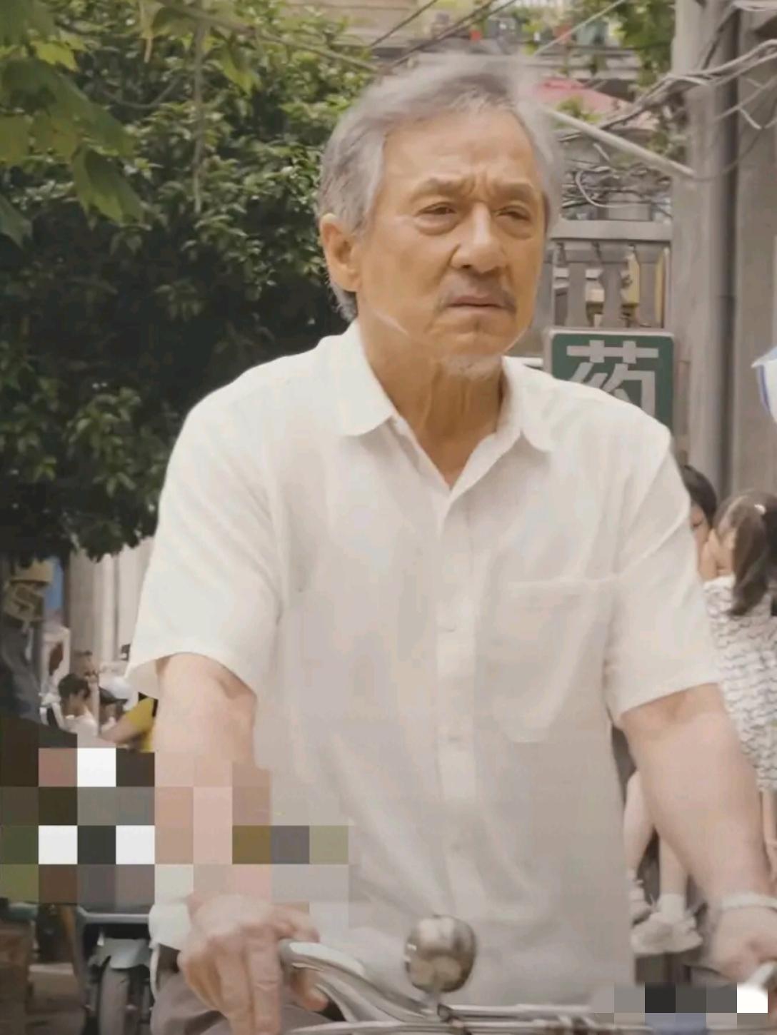 镜头中的成龙满头银发，眼角耷拉，双颊塌陷，皮松肉垮，额纹深刻，颈纹清晰，嘴型缩小