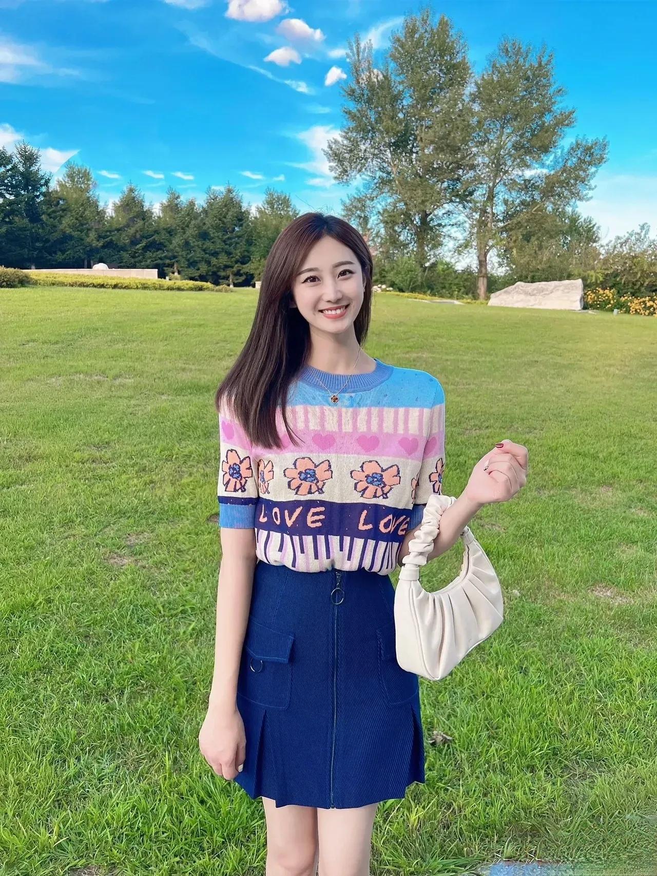 阳光明媚的午后，少女在绿草如茵的公园里微笑，穿搭清新可爱，LOVE字样甜美动人。