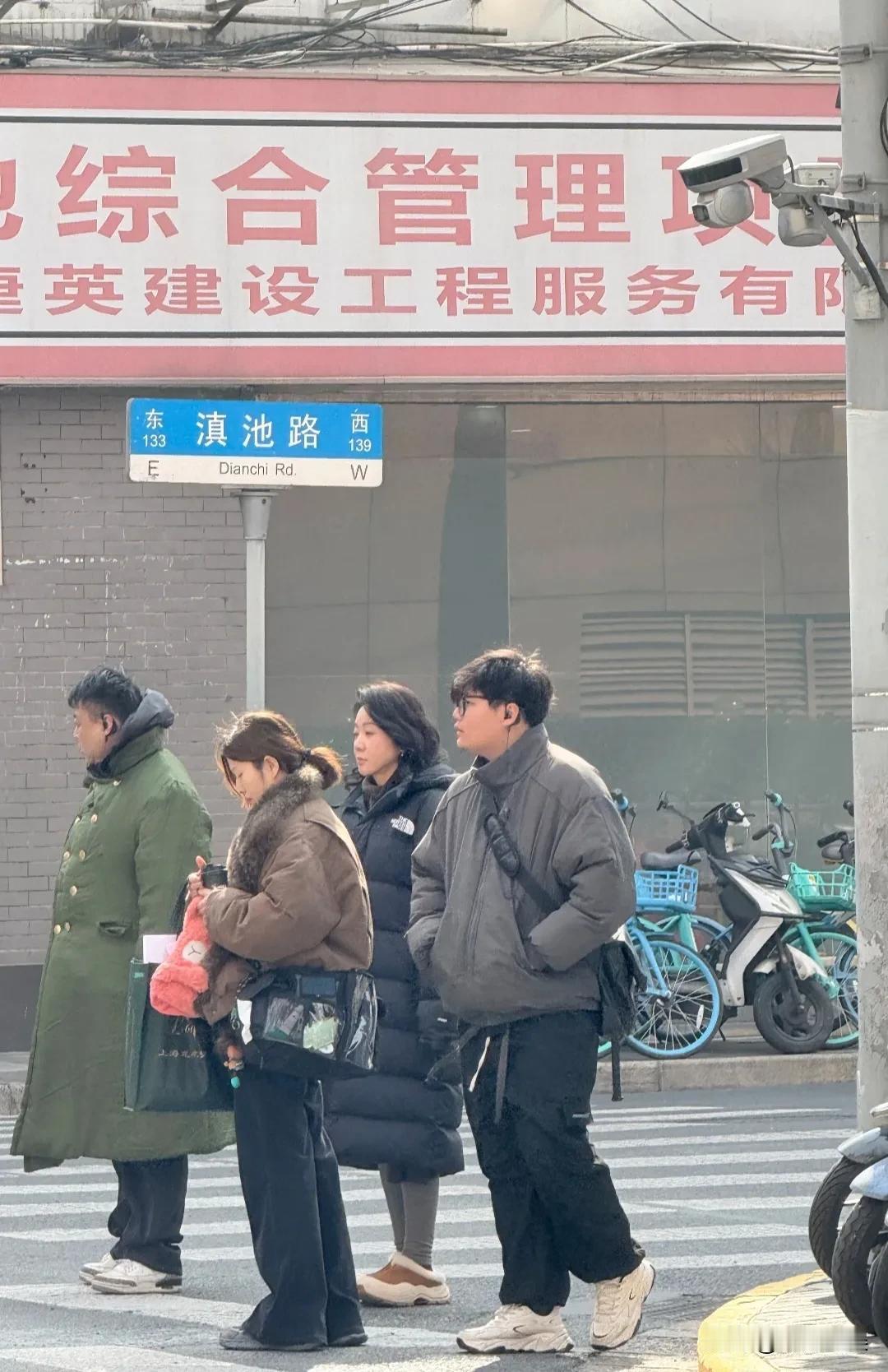 闫妮在上海拍戏，留着一头短发，穿着一件黑色的长款羽绒服，紧身裤搭配毛拖鞋，这么冷