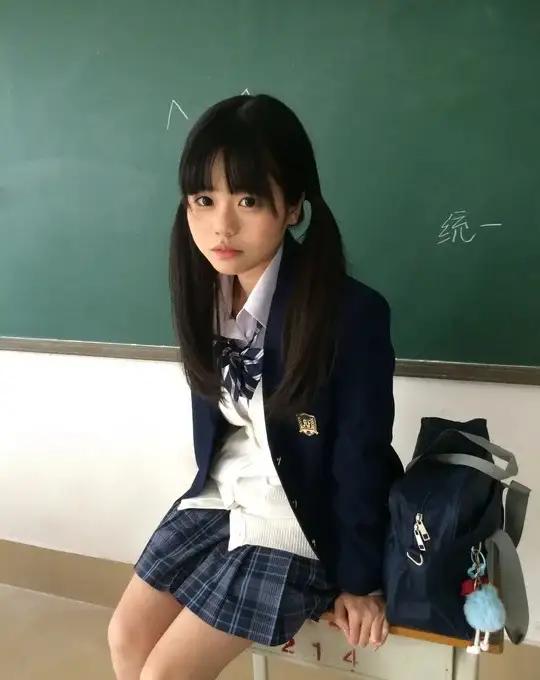 教室里的女生穿着校服，坐在讲台边。教室美女课堂美照