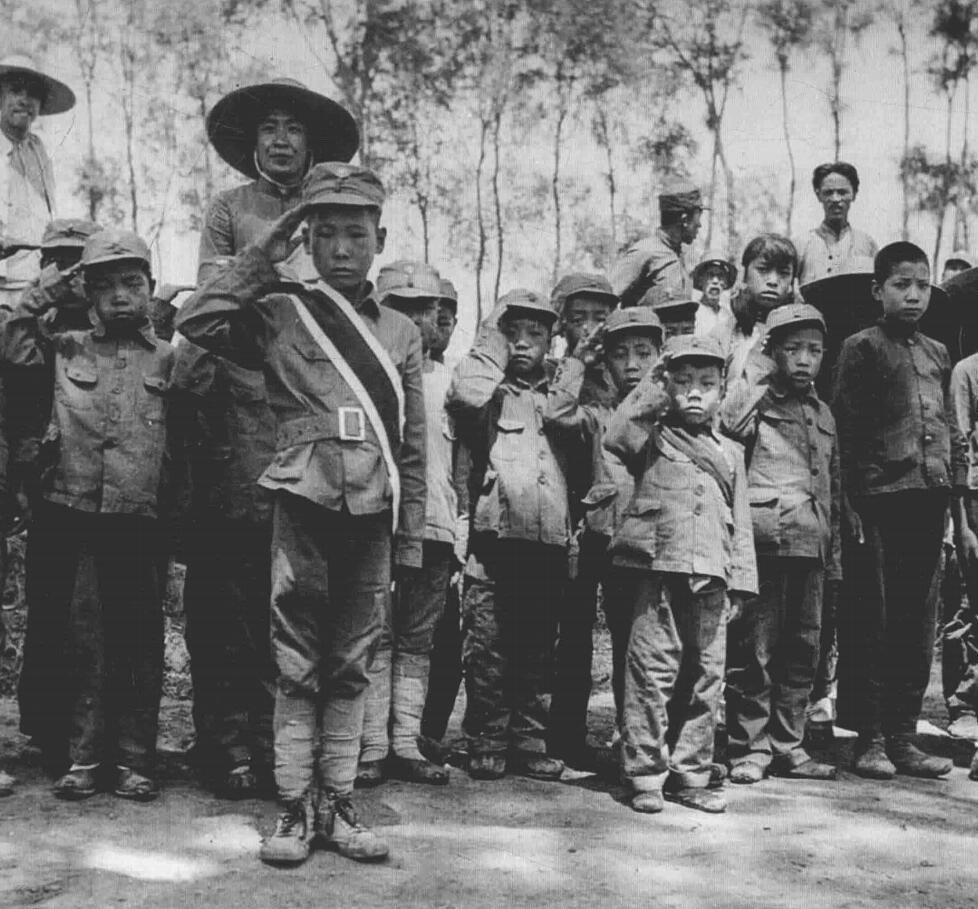 历史知识1940年，河北。中国儿童在为来访的美国军事观察员唱爱国歌曲和向他们敬礼