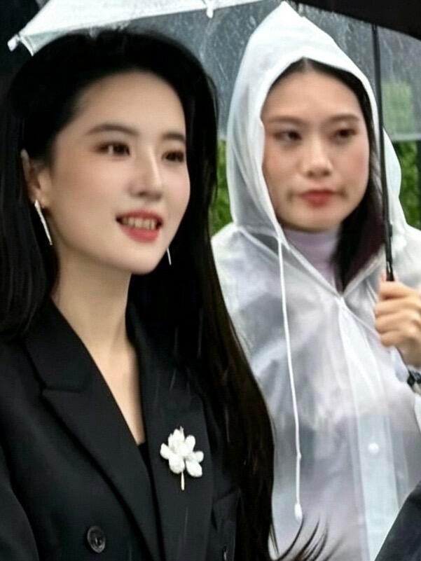 黑衣白花雨中赴约，刘亦菲的氛围感太绝了雨中现身活动现场，一身利落黑色西装，