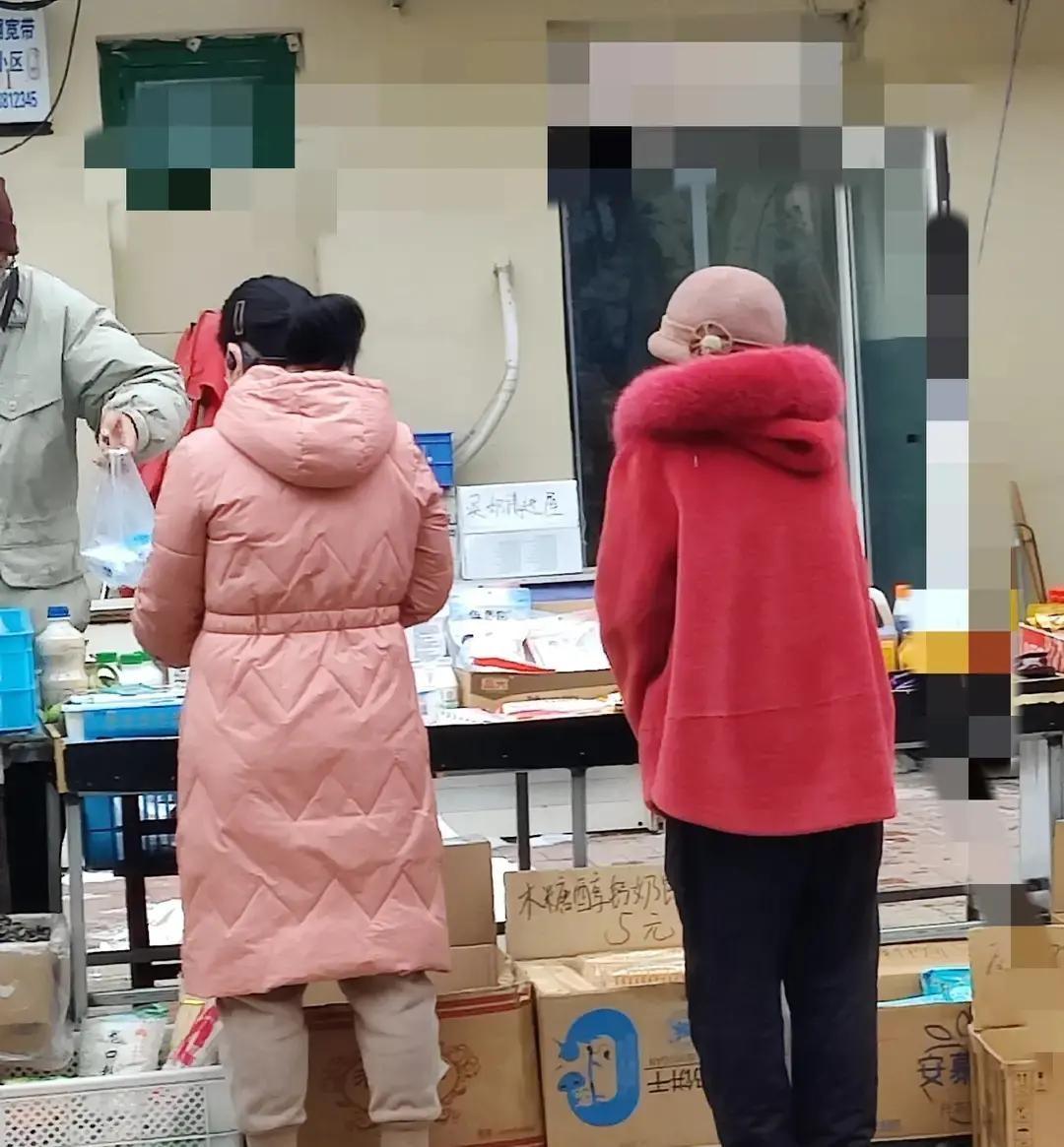 早市上，一个穿酒红羊绒大衣的女人走过去，旁边那件灰扑扑的羽绒服瞬间成了背景板。