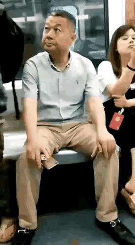 一男子坐在地铁上，身旁站在一位穿着黑色碎花短裙的女子。他趁着女子正背对着自己，便