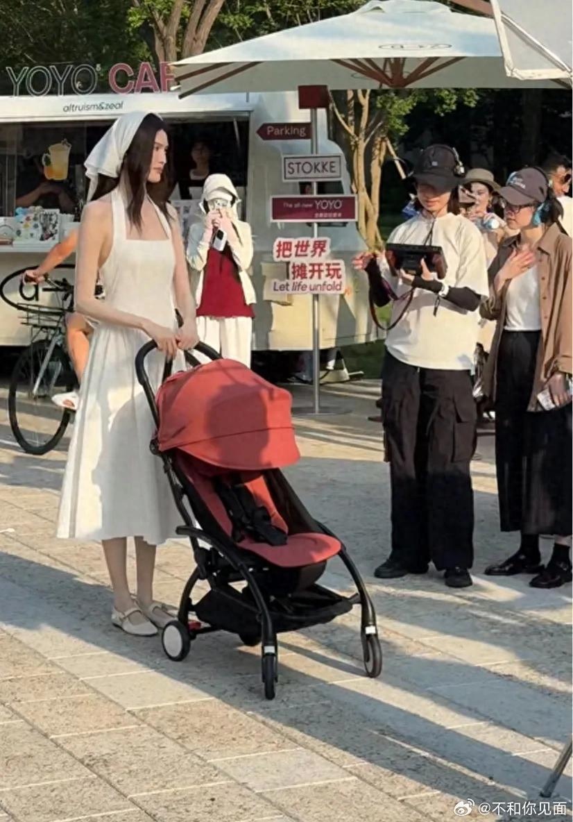 何穗在阿那亚拍婴儿车广告，戴白色头巾皮肤特别白，但整个人的颜值看着挺普通的