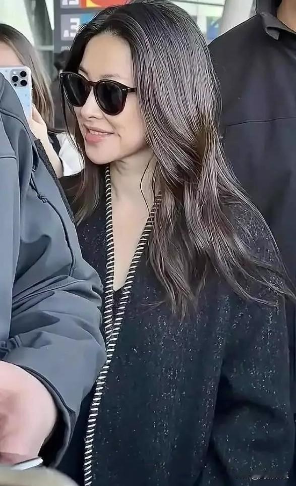 有网友在机场撞见朱珠，她穿黑长款大衣，领口白线设计独特，戴墨镜慢步，虽不特别耀眼