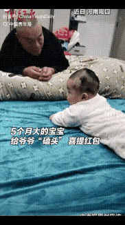 5个月大的宝宝火了！近日，河南周口，一老人趴在床边逗孙子玩，奶奶在一旁说：“给爷