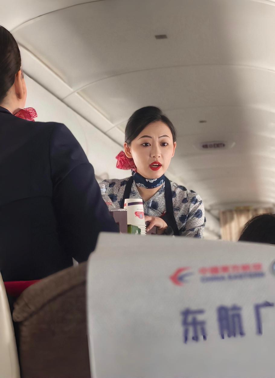 空姐在飞机上热情服务，乘客们安心享受旅程。