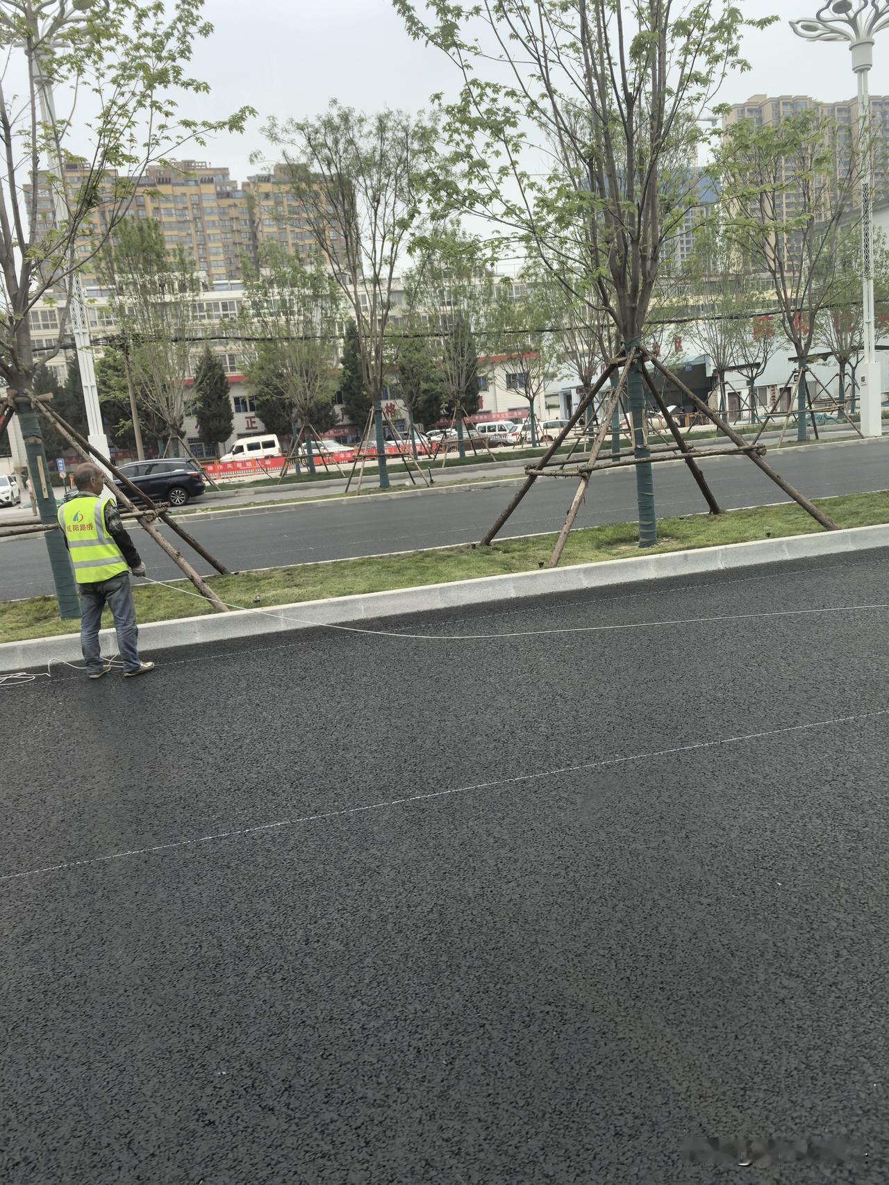 昨天，在咸阳安谷地铁站口，小编同样看到这些穿绿色工服的工人，正在给路面的道沿上铺