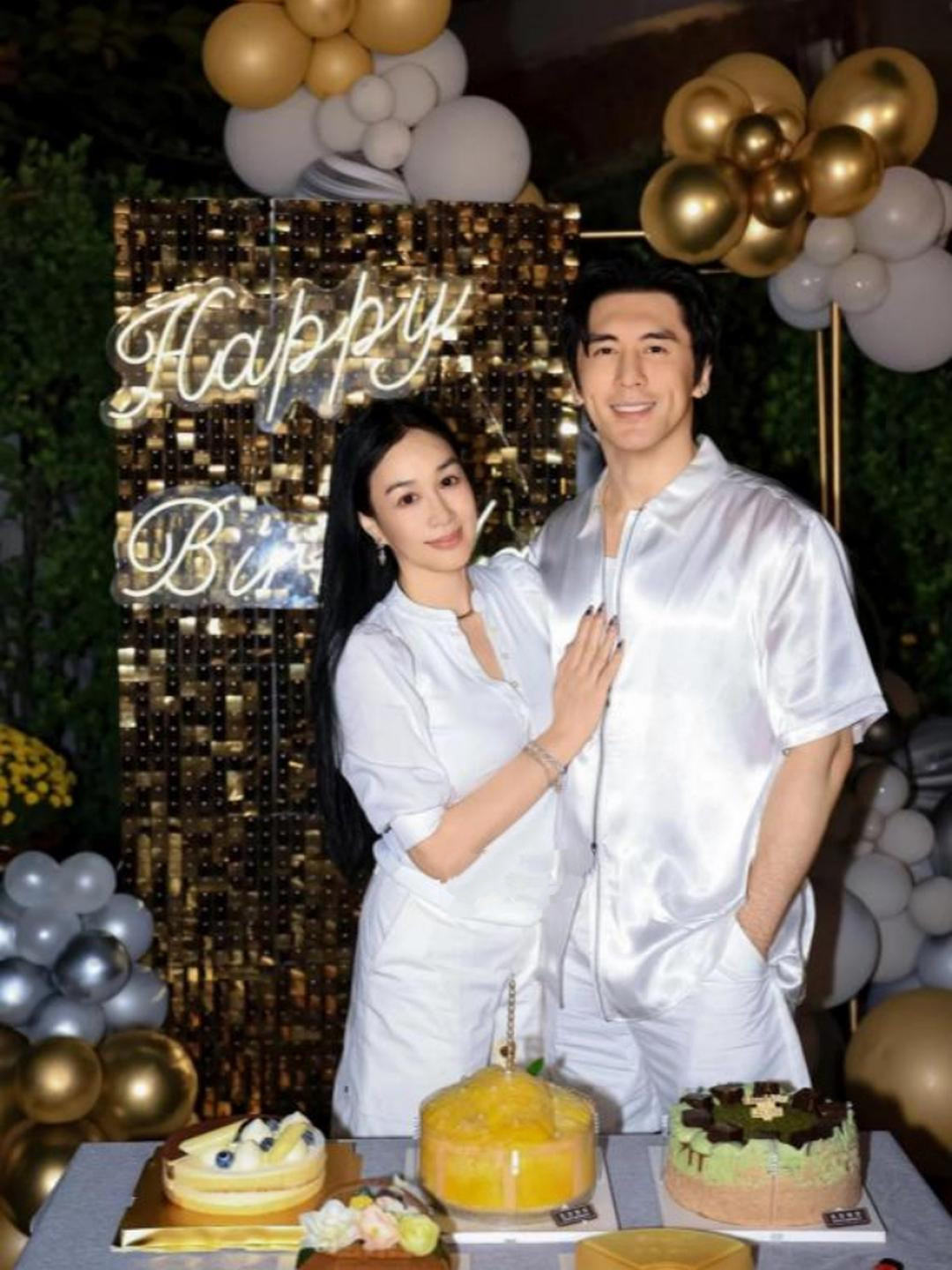 56岁钟丽缇过生日，晒和老公张伦硕合影，夫妻俩身穿同款白色丝绸面料居家服，前面摆放着生日蛋糕，两人紧